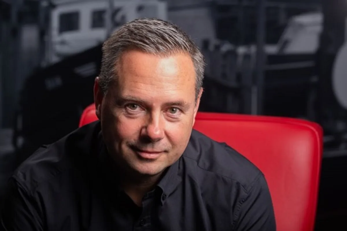 Smiling man seated on a red chair.